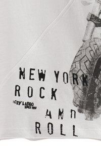 Camiseta de algodón blanca con un gráfico negro de una llanta y texto que dice "NEW YORK ROCK AND ROLL" en un estilo de fuente desgastada.