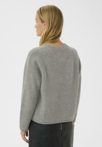 Pull en tricot gris avec texture côtelée, col rond et épaules tombantes, présenté de dos. Il dispose d'un ourlet droit.