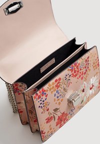 Sac à main à motif floral avec une forme structurée, doté d'un fermoir métallique, d'une bandoulière en chaîne et de couleurs intérieures contrastantes.