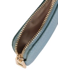 Penízková taška se zipem vyrobená z texturovaného materiálu v odstínu modro-zelené s pozlaceným kováním. Disponuje hladkou podšívkou a výrazným zipem, který odhaluje vnitřní prostor.