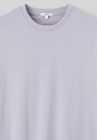 T-shirt lavande clair avec un col rond, des manches courtes et une texture douce. L'étiquette indique "BZB" et la taille "L". Pas de motifs ni de graphiques.