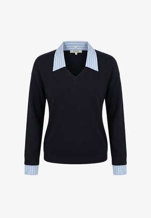 Maglione nero a scollo a V indossato sopra una camicia a righe blu e bianche con colletto e polsini coordinati visibili.