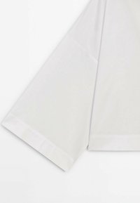 T-shirt blanc à manches courtes en tissu lisse avec des coutures nettes le long de l'ourlet et des bords des manches.