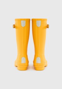 Κίτρινες λαστιχένιες μπότες βροχής με λεία επιφάνεια, που διαθέτουν ασημί λεπτομέρειες και υφασμένους λαβές, σχεδιασμένες για αδιάβροχη προστασία.