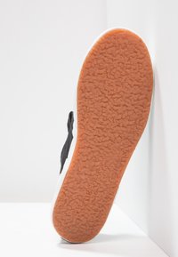 Schwarze Sneakers mit strukturiertem Gummisohle; weiße Zwischensohle; glattes Obermaterial mit Logos; entworfen für den Freizeitgebrauch. Die Sohle verfügt über ein strukturiertes Grip-Muster.