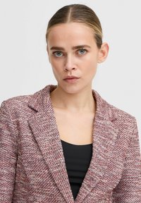 Rot-weißer, strukturierter Blazer mit Reverskragen, Ein-Knopf-Verschluss und einem schwarzen Innenoberteil, der eine maßgeschneiderte Passform betont.