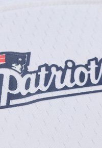 Weißer Stoff mit dem Wort "Patriots" in Marineblau, mit einem Emblem, das in der linken oberen Ecke eine Figur mit Hut zeigt. Strukturierte Oberfläche.
