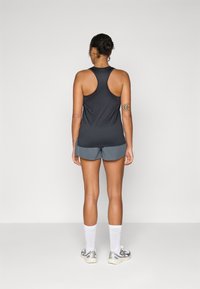 Sport tank top in black, grey athletic shorts, white crew socks, and silver sneakers; features racerback design and smooth fabric.