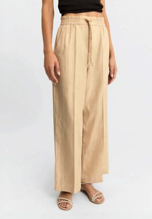 Pantaloni beige a gamba larga con sottili righe verticali, vita elastica con coulisse, indossati con sandali beige e top corto nero.