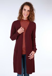 Burgundy textured cardigan with open front, long sleeves, and pockets, layered over a striped turtleneck. Casual fit with a soft finish.