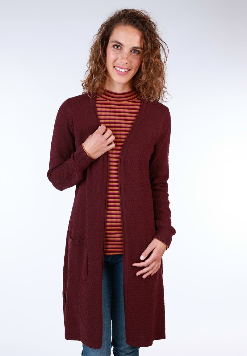 Burgundy textured cardigan with open front, long sleeves, and pockets, layered over a striped turtleneck. Casual fit with a soft finish.