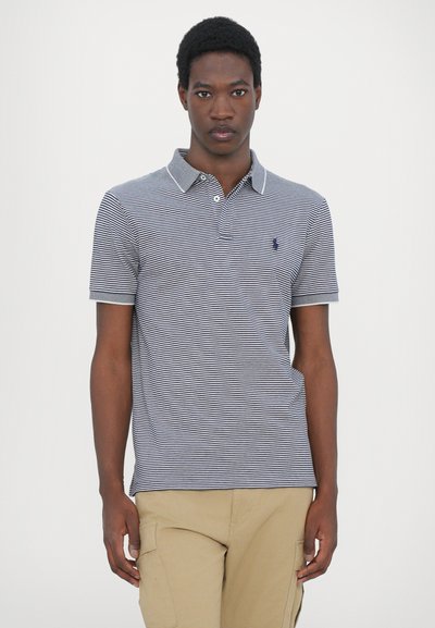 Camisa polo a rayas en azul marino y blanco, con cuello y mangas cortas. Acentuada con un pequeño logo en el lado izquierdo del pecho. Tejido de algodón.