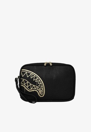 Bolso de muñeca rectangular negro con cremallera dorada y gráfico parcial de boca de tiburón dorada en el lado frontal izquierdo.
