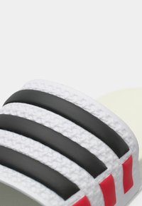 Μαύρο και άσπρο σανδάλι slide με τρεις υφασμάτινες μαύρες ρίγες, κόκκινες λεπτομέρειες και επένδυση σόλας με μαξιλάρι, με λείο, ματ φινίρισμα.