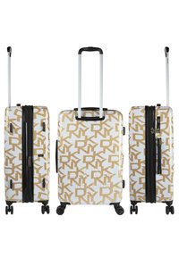 Maleta rígida con un fondo blanco y un patrón geométrico dorado, cremallera negra y asa retráctil sobre cuatro ruedas.