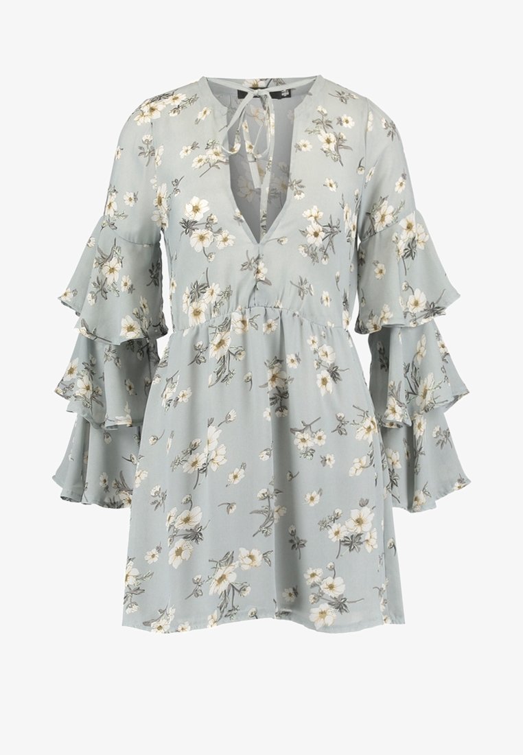Robe florale en tissu bleu clair avec un décolleté en V, des manches cloche volantées et une taille ajustée. Elle présente des motifs de fleurs blanches et jaunes.