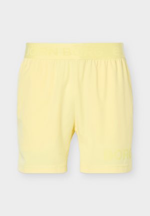 Gelbe Shorts mit elastischem Bund und dezentem Branding am Bund und am unteren linken Bein, dargestellt vor schlichtem hellgrauem Hintergrund.