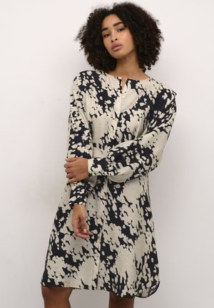 Abito camicia button-up in crema e blu navy con motivo astratto, maniche lunghe e vestibilità comoda; presenta una piega sul retro e polsini.