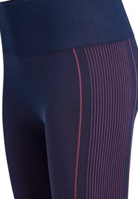 Zbliżenie granatowych legginsów z wysokim stanem i pionowymi różowymi paskami wzdłuż bocznego szwu.