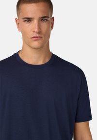 Námořnická modrá tričko vyrobené z měkké látky, s klasickým kulatým výstřihem a krátkými rukávy, s hladkým povrchem a bez viditelných vzorů či doplňků.