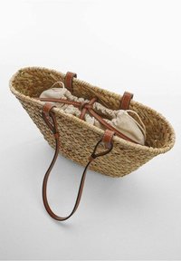 Pleciony koszyk ze słomy o zaokrąglonym kształcie, z brązowymi skórzanymi uchwytami i beżową podszewką ze sznurkiem do ściągania. Teksturowana powierzchnia z naturalnych włókien.