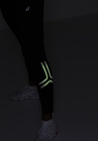 Czarne legginsy sportowe z odblaskowymi akcentami w geometryczny wzór. Materiał odprowadza wilgoć, zaprojektowany z myślą o komforcie podczas ćwiczeń.