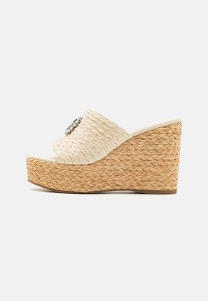 Sandalia beige de cuña tejida con punta abierta, suela de plataforma y adorno decorativo plateado en la tira.