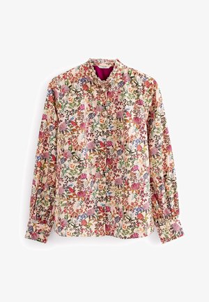 Langærmet bluse med blomsterprint, høj flæsekant, knapper foran og flerfarvet mønster af pink, lilla, grøn og orange blomster på cremefarvet baggrund.