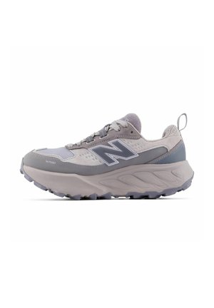Grau und hellvioletter New Balance Laufschuh mit dicker Sohle, Schnürung vorne, atmungsaktivem Mesh-Gewebe und "Toe Protect" an der Vorderseite.
