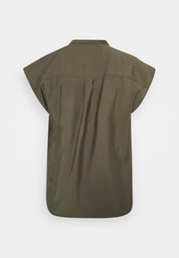 Blusa verde oliva a maniche corte con yoke posteriore dritto, vestibilità ampia e un tessuto leggermente testurizzato.