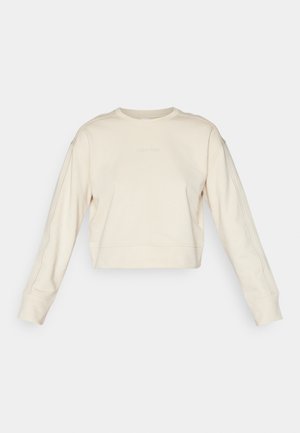 Sweatshirt bege cropped com mangas longas, decote redondo e logótipo discreto da Calvin Klein, apresentando punhos canelados e textura sólida.