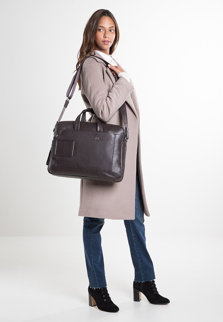 Borsa a mano in pelle marrone con due manici e tracolla removibile. Superficie texture, forma rettangolare, con tasca frontale e branding discreto.