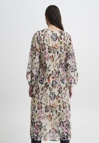 Blumenkleid im Maxiformat aus transparenter Stoff. Es hat lange, gepuffte Ärmel, einen gefältelten Rücken und einen hellbeige Grundton mit mehrfarbigen Blumenmustern.