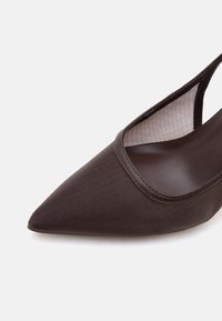 Κοντινή λήψη ενός σκουρό καφέ παπουτσιού slingback με μυτερή μύτη, λείου υφής επάνω μέρος και ορατή εσωτερική επένδυση.