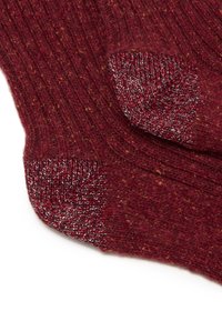Calze a maglia borgogna con texture a coste e dettagli metallici sulla punta e sul tallone. Il tessuto morbido presenta delicate variazioni di colore.