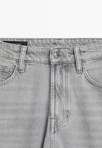 Gray denim jeans featuring a classic five-pocket design, metal button closure, and subtle fading details along the fabric.