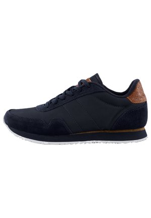 Baskets de sport bleu marine en cuir et daim, avec un talon texturé brun, une semelle blanche et des rayures grises contrastantes sur le côté.