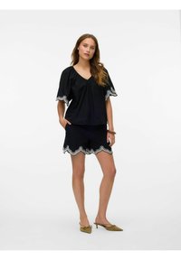 Set di top e pantaloni corti neri con orlo a scallop, impreziosito da ricami bianchi. Maniche corte e design con scollo a V. Realizzato in un tessuto leggero.
