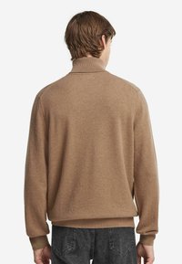 Brun pullovertröja med hög krage, ribbade manschetter och nederkant, mjuk textur, med avslappnad passform och minimalistisk design.