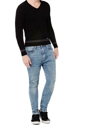 Czarny sweter z dekoltem w serek i długimi rękawami, zestawiony z jasnoniebieskimi dopasowanymi jeansami. Czarne trampki z białą podeszwą podkreślają casualowy charakter stylizacji.