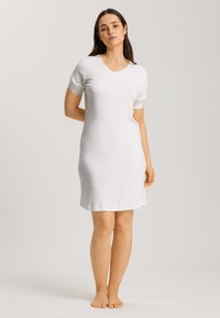 Camisón blanco de manga corta con escote en V, que presenta una textura suave y un diseño ajustado que llega justo por encima de la rodilla.