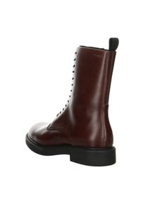 Bottine en cuir marron à finition lisse, bout arrondi et semelle en caoutchouc noire. Dotée d'un laçage décoratif sur le côté.