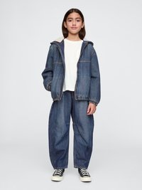 Denim jacket with hood, light gray lining; white T-shirt; loose-fitting denim pants. Black and white striped sneakers.
