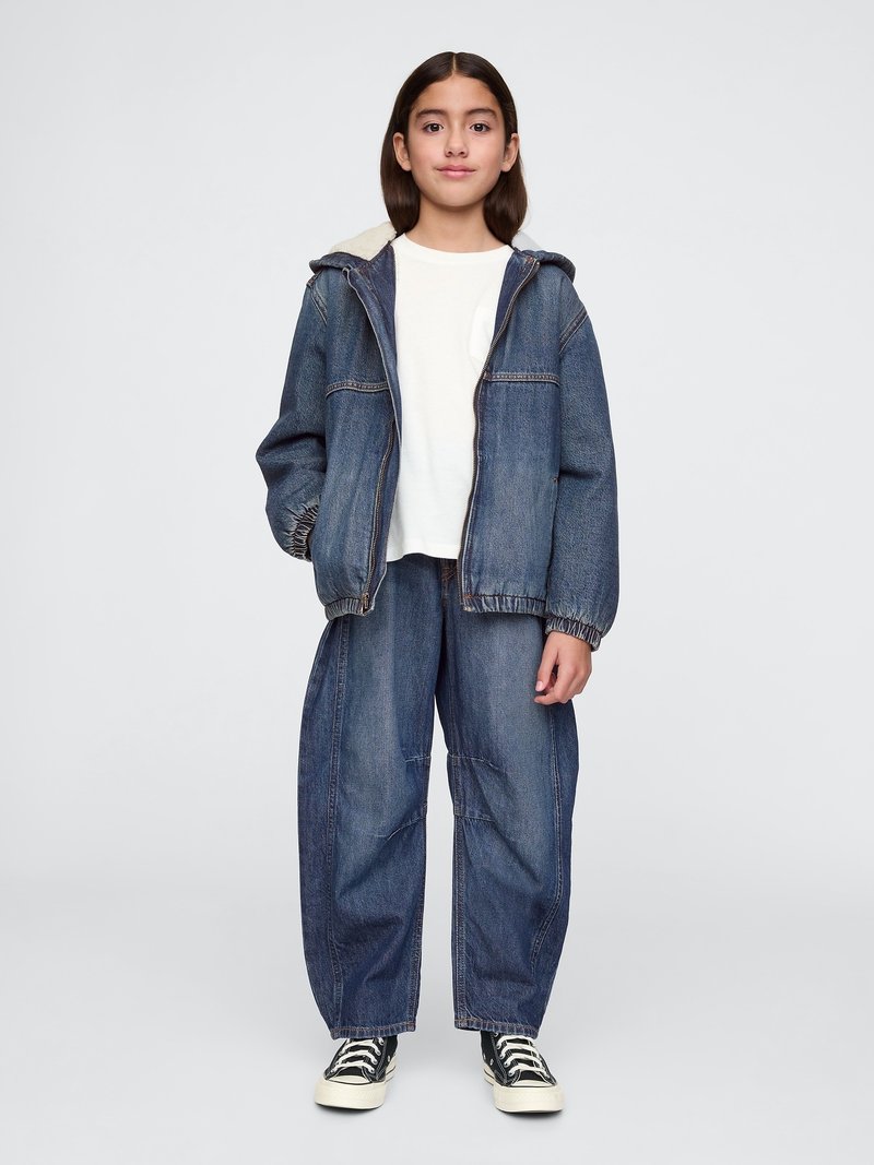 Denimjacke mit Kapuze, hellgrauem Innenfutter; weißes T-Shirt; locker sitzende Denim-Hose. Schwarz-weiße gestreifte Sneakers.