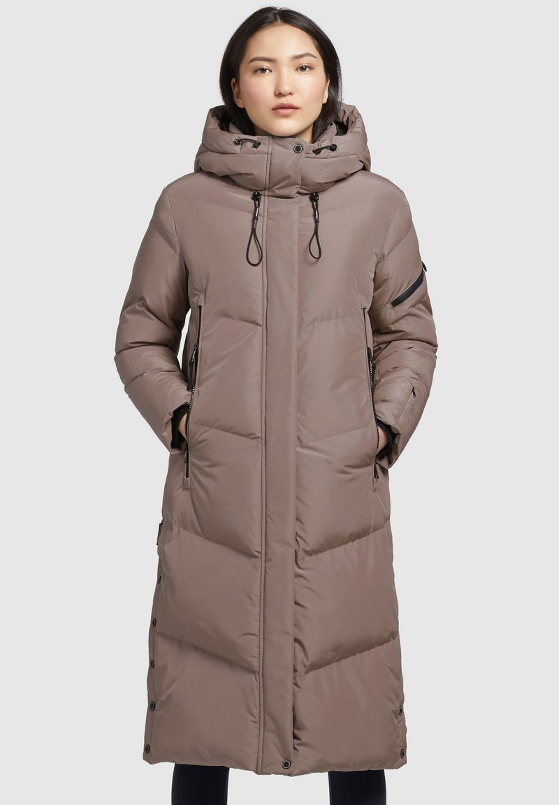 Cappotto lungo imbottito in taupe con cappuccio. Presenta dettagli con cerniera nera, tasche laterali e bottoni a pressione lungo la parte anteriore. Tessuto testurizzato.