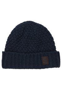Căciulă tricotată de culoare bleu marin, cu modele texturate, permite să fie pliată cu un tiv ribatat și are un mic patch din piele maro cu marca pe partea din față.