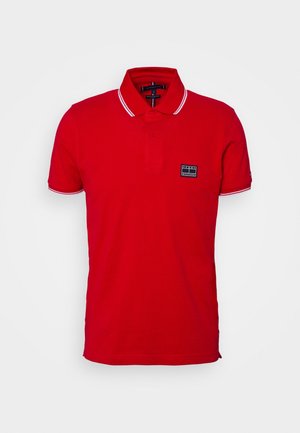 Polo rouge en coton, doté d'une patte de boutonnage à deux boutons, d'un col avec liseré blanc et d'une petite étiquette logo noire sur la poitrine.
