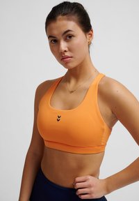Oranje sport-bh van rekbaar materiaal met een ronde halslijn, voorzien van drie marineblauwe chevrons aan de voorkant en een aansluitend ontwerp.