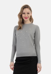 Pulover gri din material tricotat moale, având un decolteu rotund și embellishments asemănătoare cu perlele pe față. Croială ajustată cu manșete ribbate.