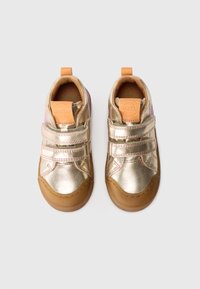 Złote metaliczne sneakersy z dwiema paskami na rzepy, w odcieniu tan, oraz teksturowaną gumową podeszwą. Zaprojektowane z myślą o komforcie i trwałości.